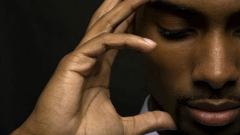 A person holds a hand to their head