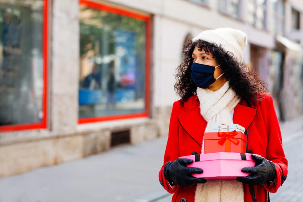 A woman holding gifts looks at shop windows