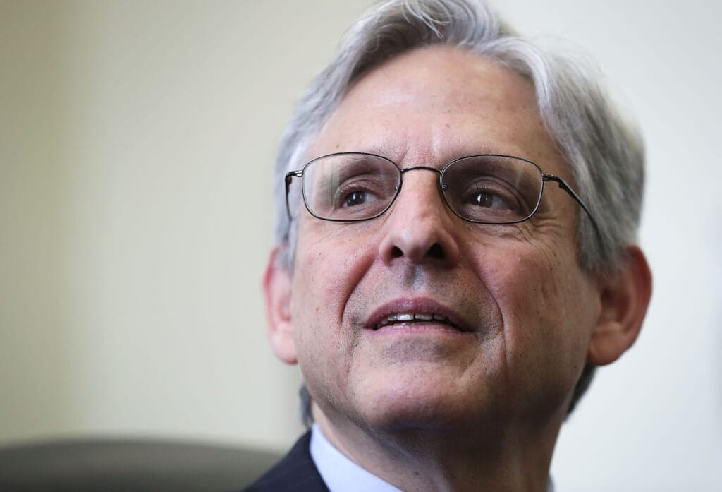 U.S. Attorney General Merrick Garland is shown wearing a dark blue jacket and white shirt