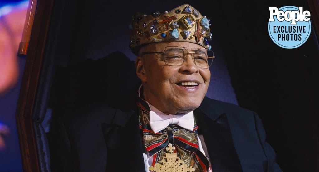 Actor James Earl Jones in "Coming to America," wearing a crown with large jewels, a navy jacket and a white bowtie