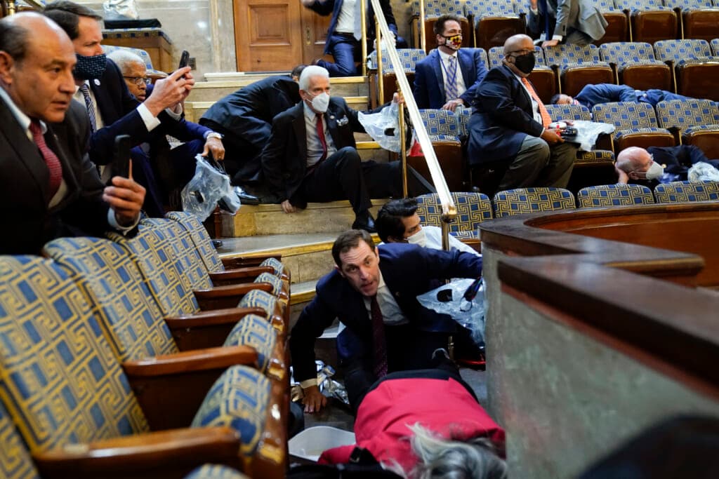 People shelter in the House gallery as protesters try to break into the House Chamber at the Capitol on Jan. 6, 2021