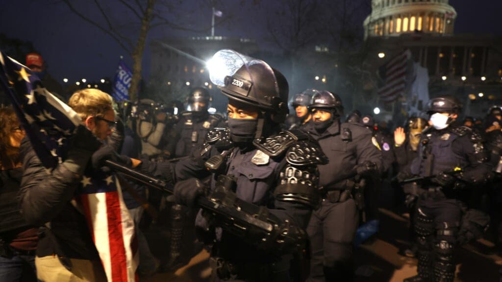 Police officers in riot gear confront protesters