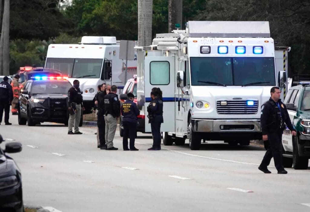 Several FBI agents and law enforcement personnel near two large white trucks