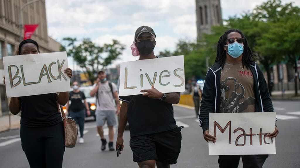 Protesters march with three placards stating “Black Lives Matter”