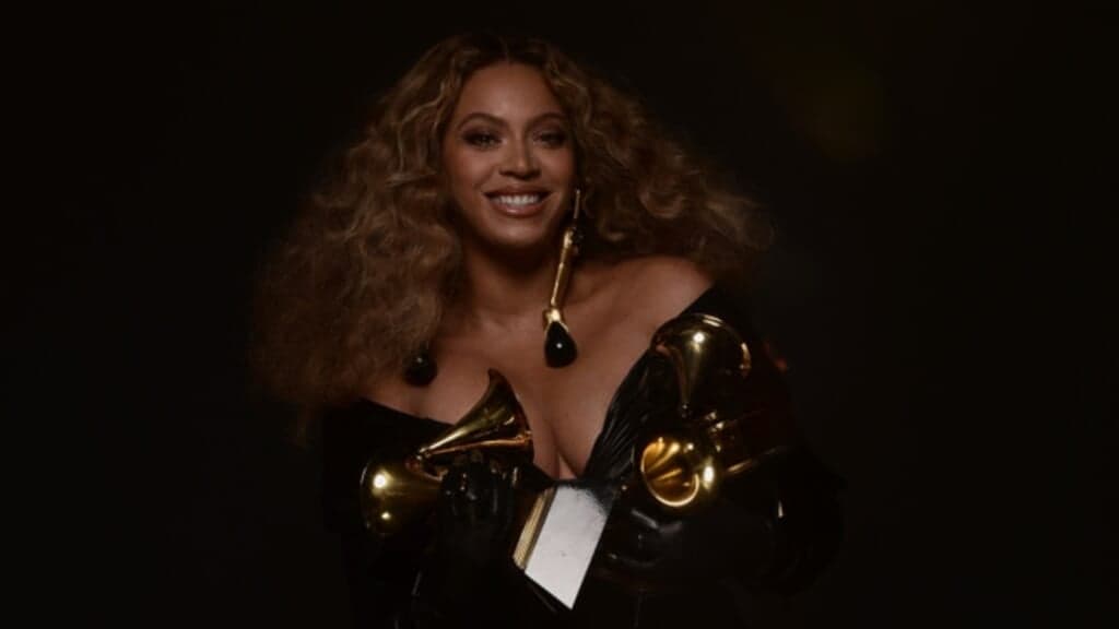 Singer Beyonce, wearing a black dress, holds two Grammy awards