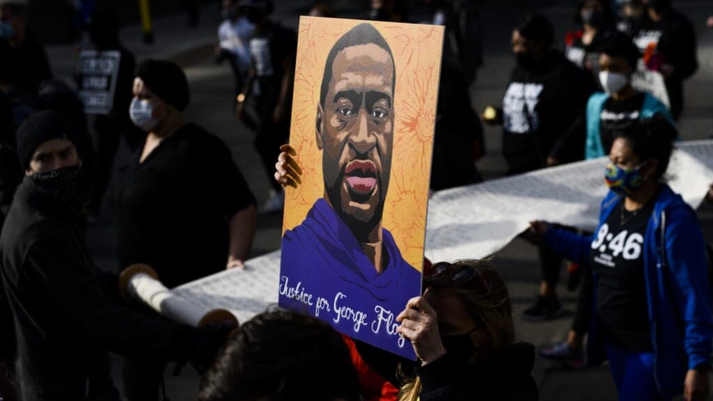 Demonstrators carry a scroll listing the names of people killed by police during a march in honor of George Floyd