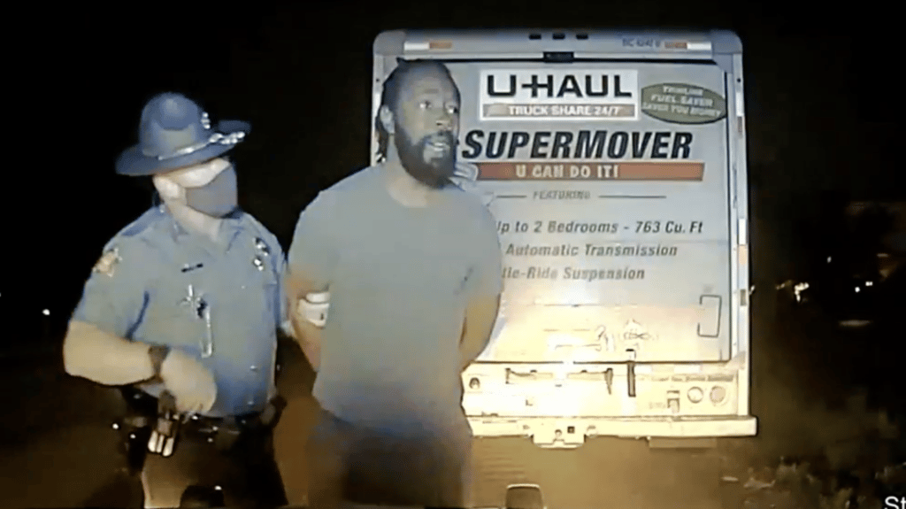 Marion Humphrey Jr., handcuffed and held by a state trooper