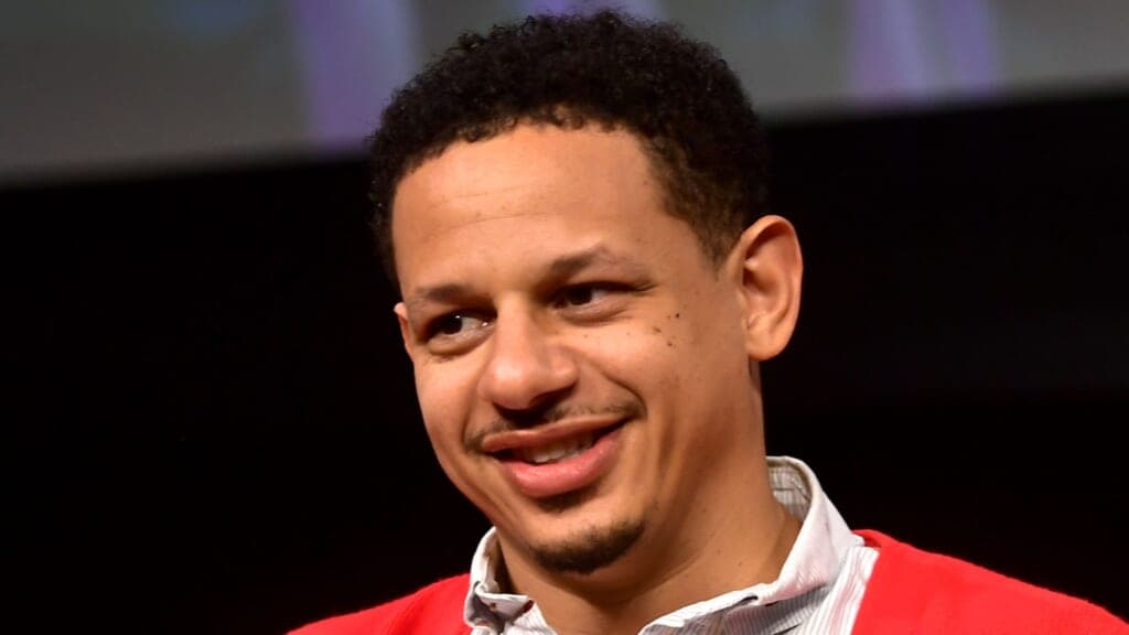 Comic actor Eric Andre wearing a red sweater and white shirt