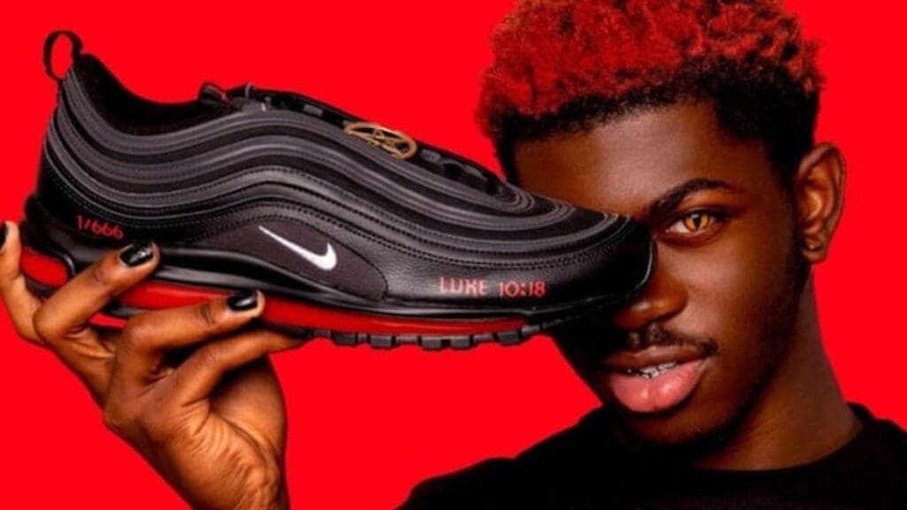 Rapper Lil Nas X holds one of his black and red so-called "Satan Shoes"