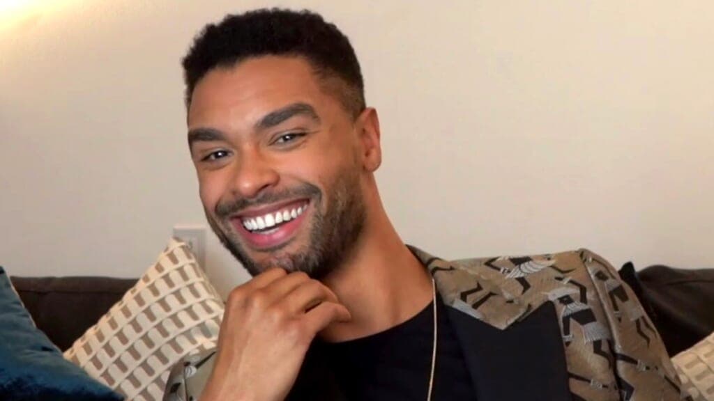 Actor Regé-Jean Page wearing a black shirt and brown patterned jacket