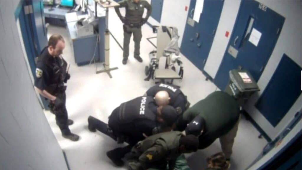 Police officers restrain a man