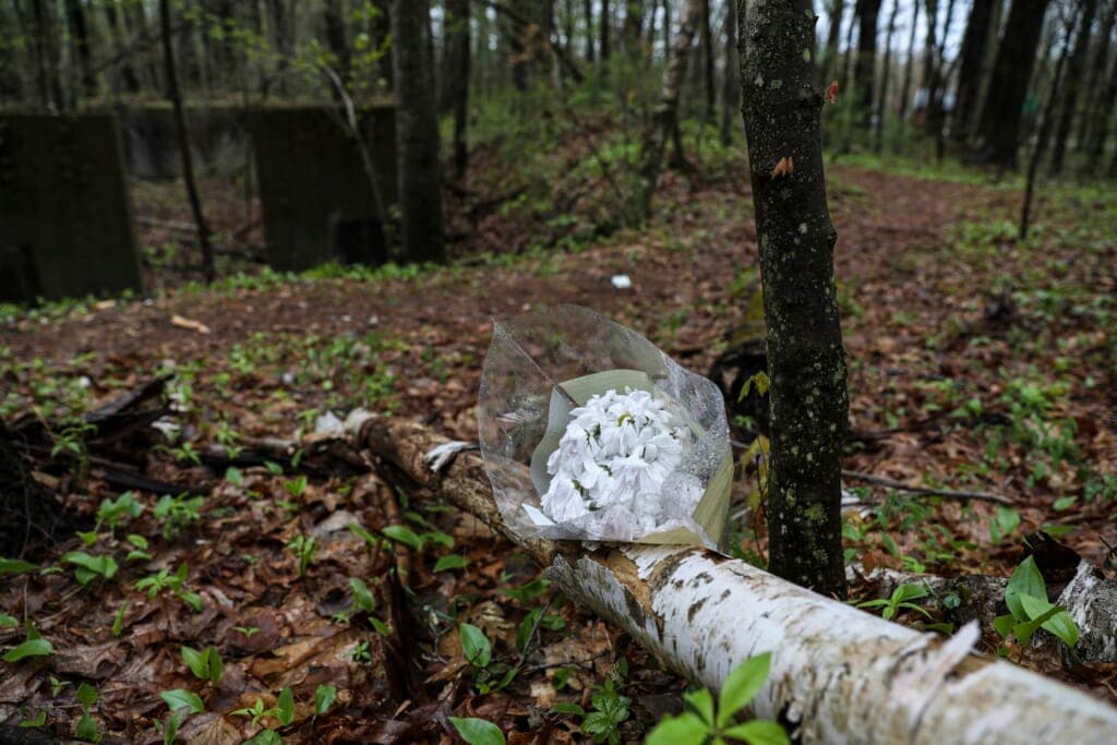 Flowers rest in the woods near where Mikayla Miller was found dead