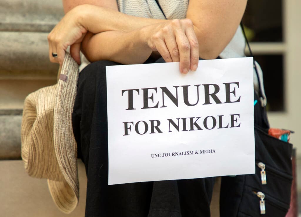 Deborah Dwyer, a doctoral candidate, holds a sign reading "Tenure for Nikole"