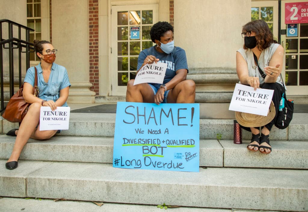 Sarah Miles, Carol Shirley and Deborah Dwyer hold signs supporting Nikole Hannah-Jones