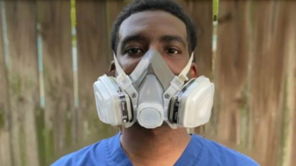 A man in medical scrubs wearing a breathing mask