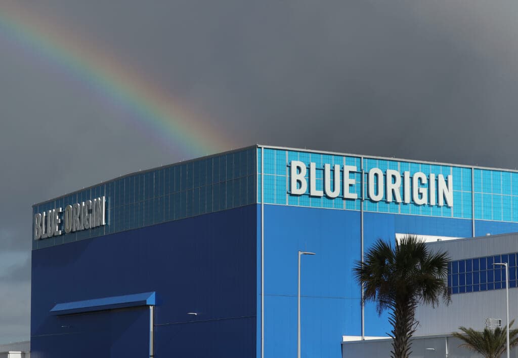 A rainbow is shown in front of dark storm clouds over Jeff Bezos' Blue Origin Aerospace Manufacturer building