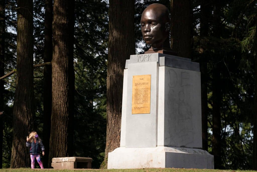A young visitor examines a statue of York, the only Black member of the Lewis and Clark Corps of Discovery