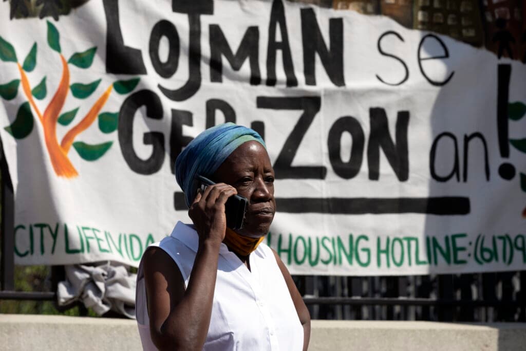A woman in front of a sign in Haitian Creole