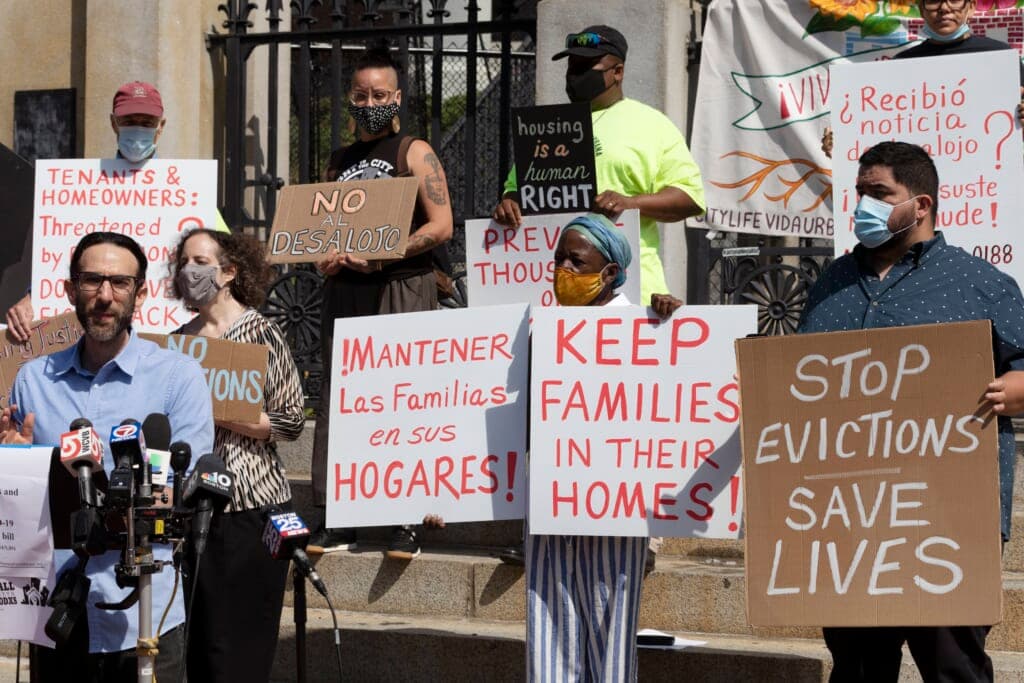 People hold signs protesting evictions