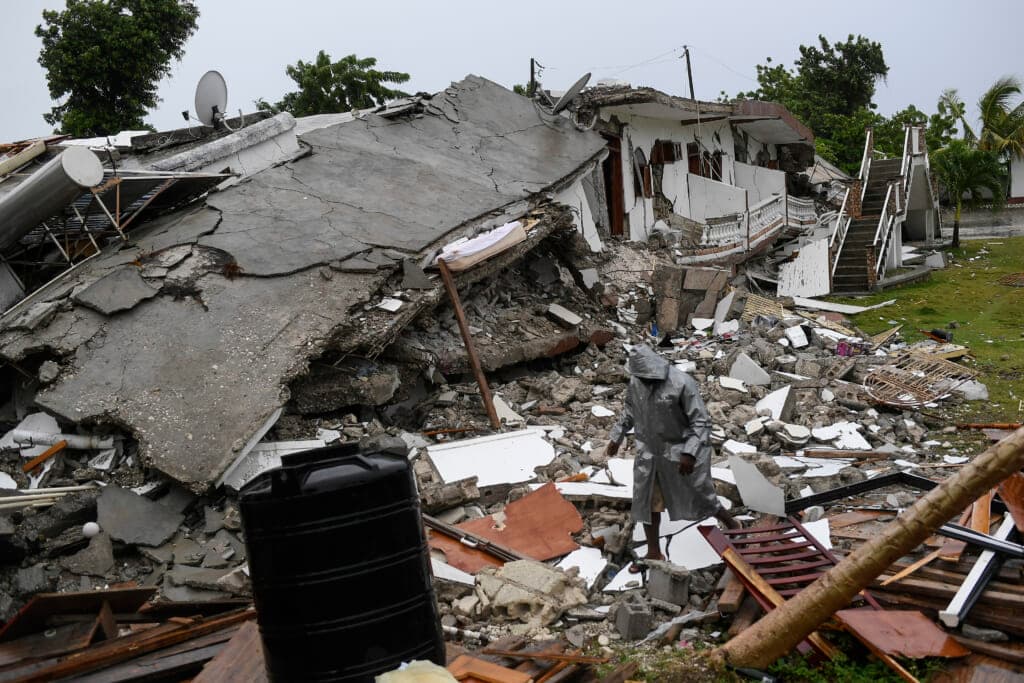 A man walks on the rubble of a collapsed hotel