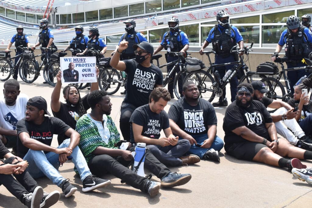 Demonstrators sit outside Terminal B/C at the Reagen National Airport. (Photo: Marconja Zor)