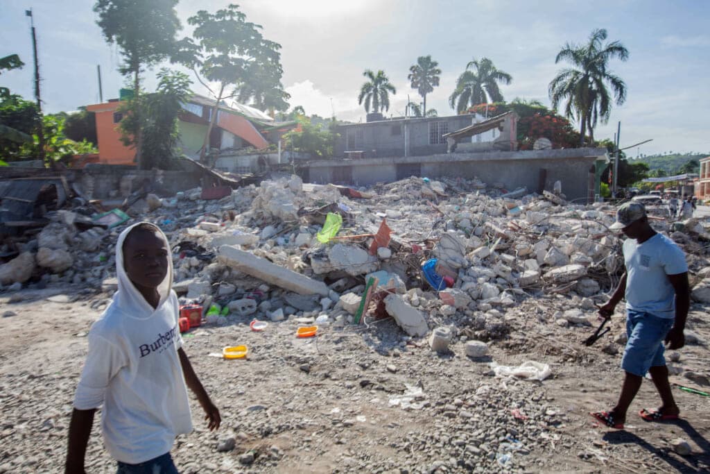 Men walk among the debris of a collapsed building after a 7.2-magnitude earthquake struck Haiti