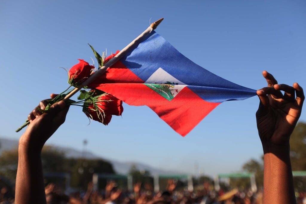 A woman holds a Haitian flag and roses