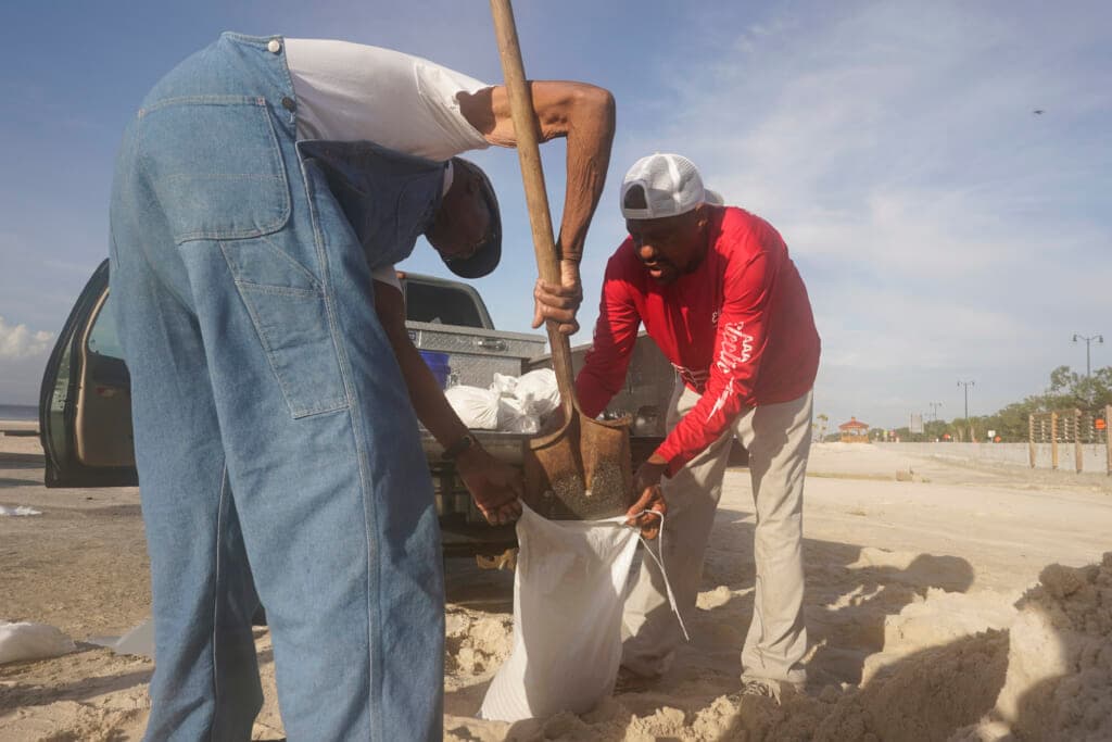 Gregory Moore, right, helps local residents fill sandbags