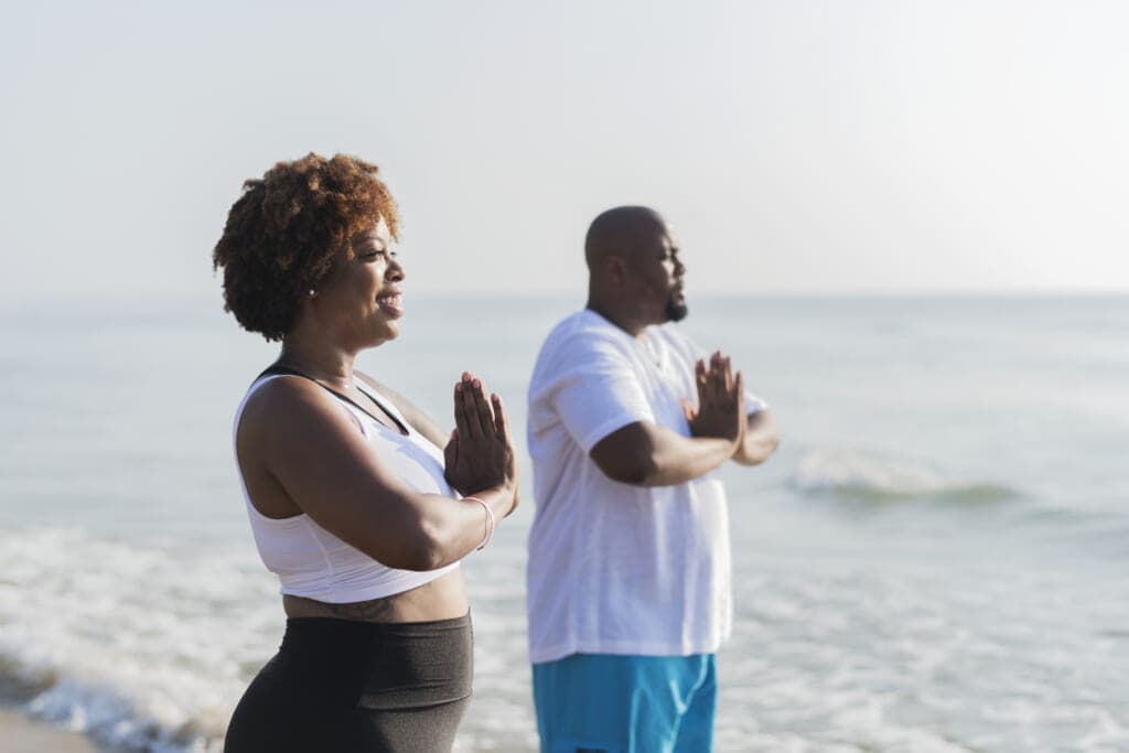 A couple doing yoga on a beach