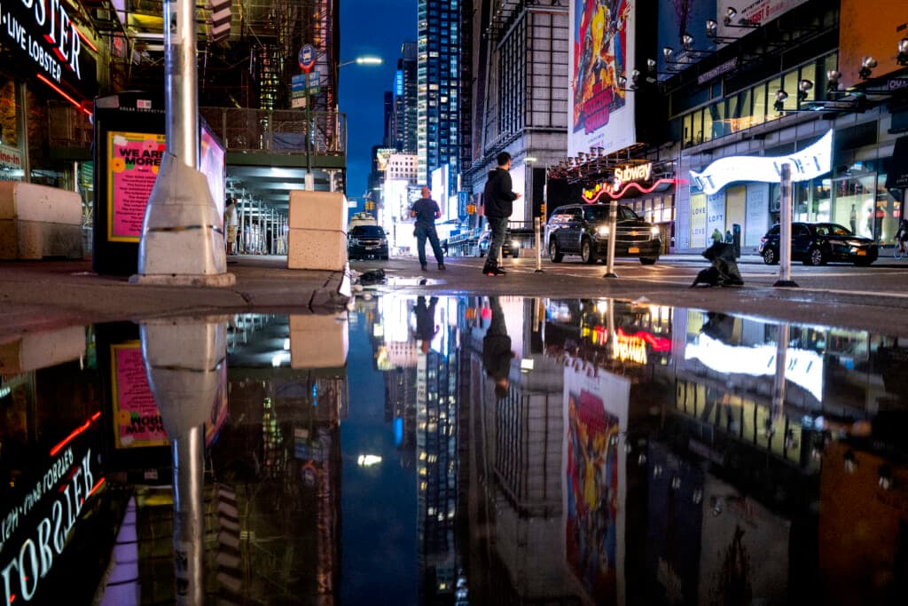 The lights of Times Square in New York reflected in standing water
