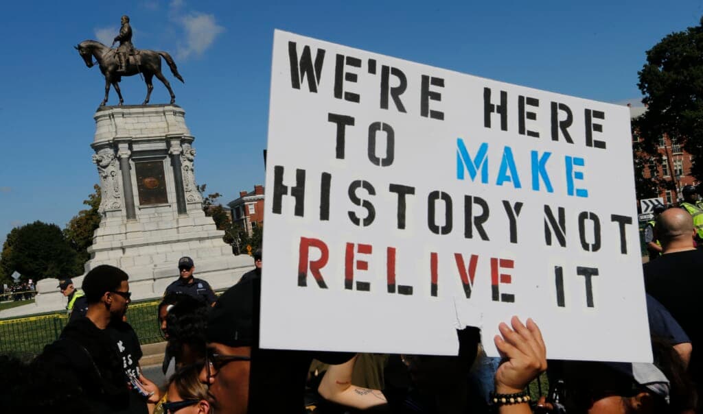 Protesters hold signs in front of a statue of Confederate General Robert E. Lee