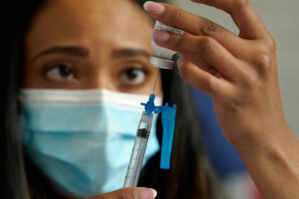 Licensed practical nurse Yokasta Castro draws a Moderna COVID-19 vaccine into a syringe