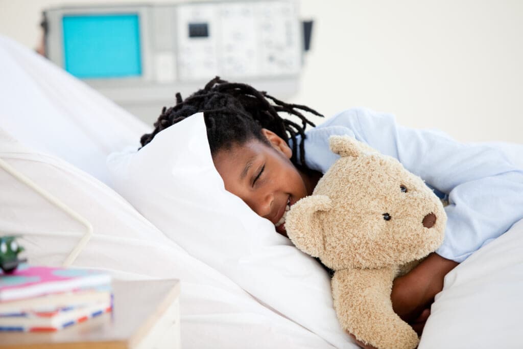 Child in a hospital bed with a teddy bear