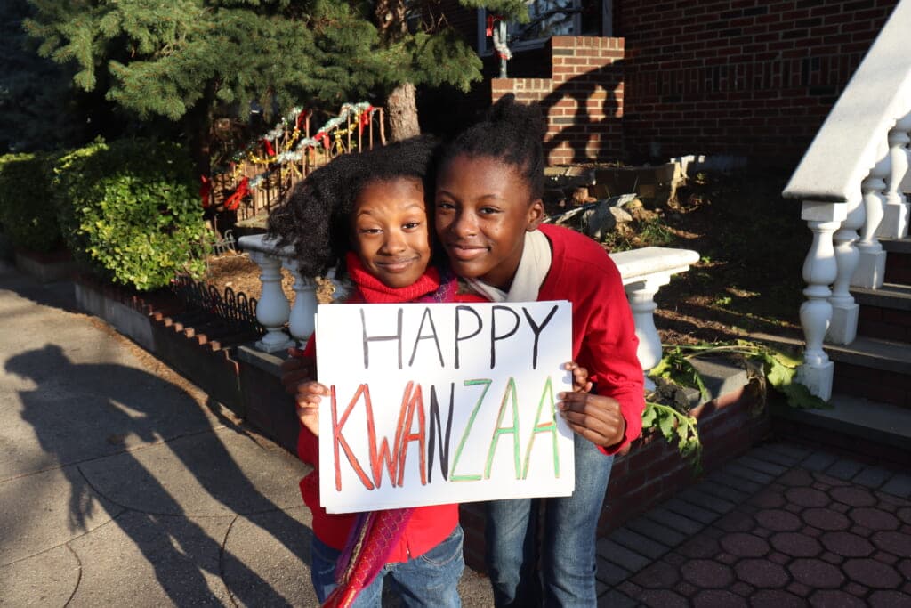 Two children hold a "Happy Kwanzaa" sign