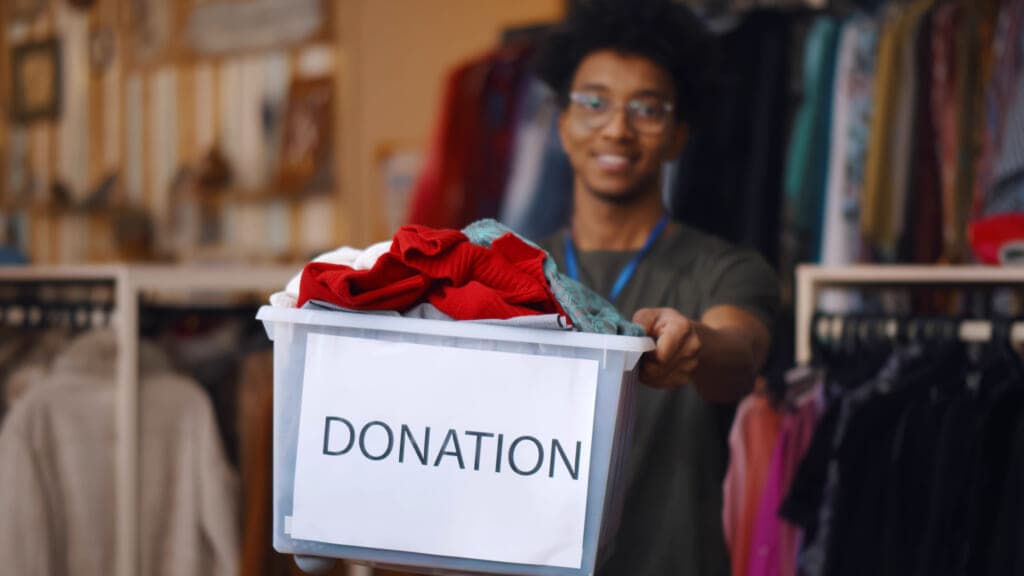 Man carrying a tub labeled "Donations"