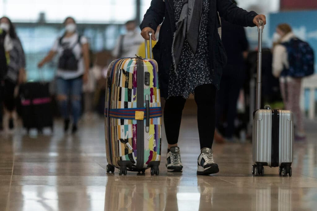 A person rolling two suitcases at an airport