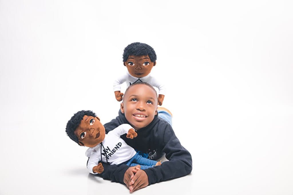 A child with two ‘Our Brown Boy Joy’ dolls