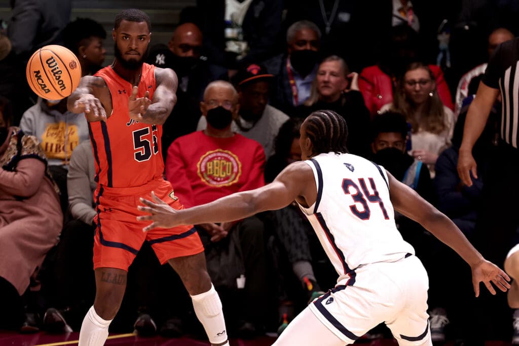 Trevor Moore of the Morgan State Bears passes a basketball past Bryce Harris of the Howard Bison