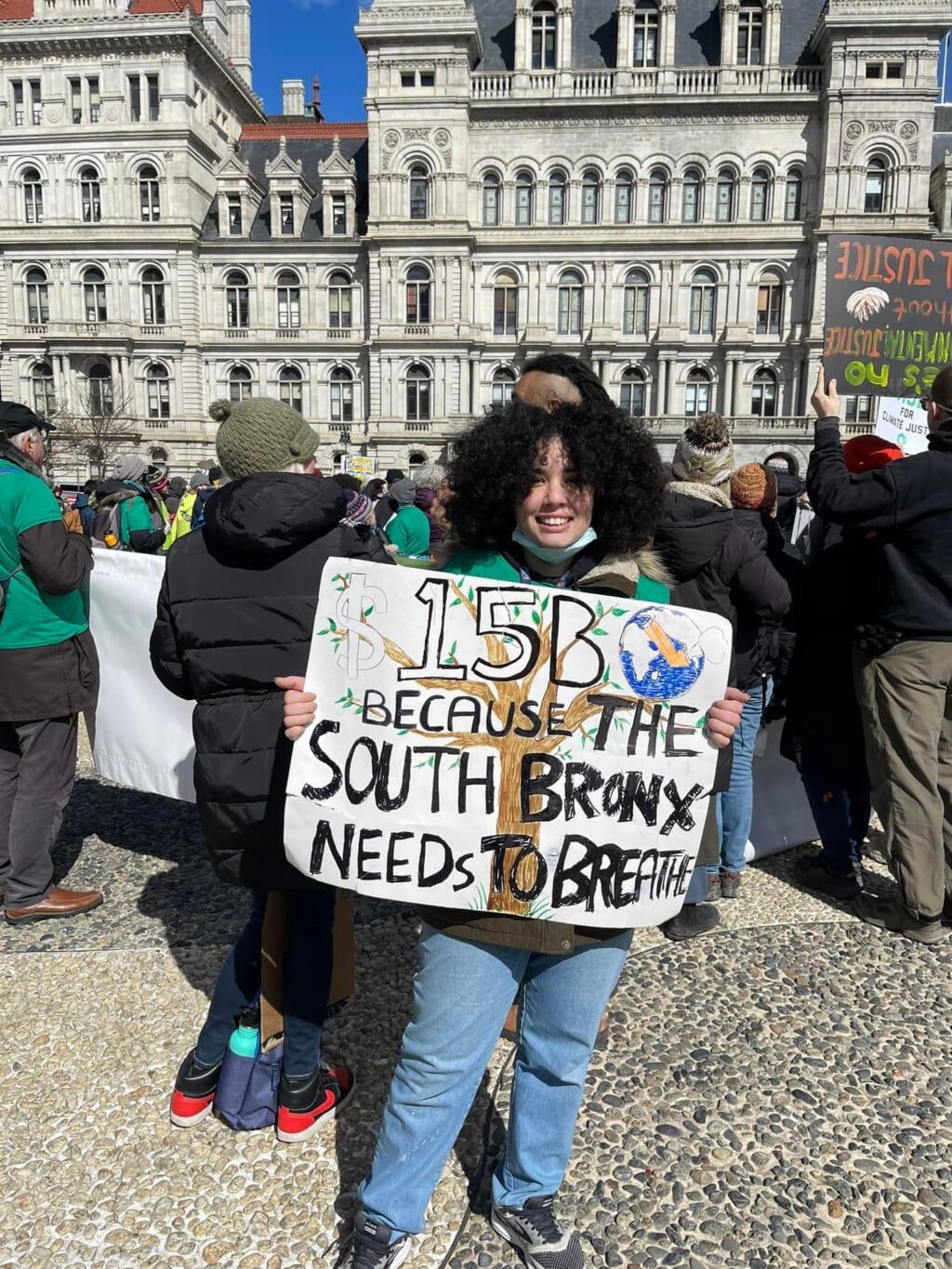 Ashley Fontanilla, a staff member of South Bronx United, wearing a black and green jacket and blue jeans