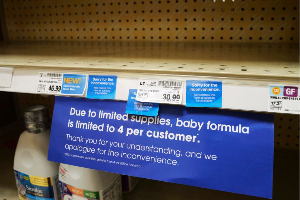 A sign concerning limited supplies is shown on the baby formula shelf at a grocery store