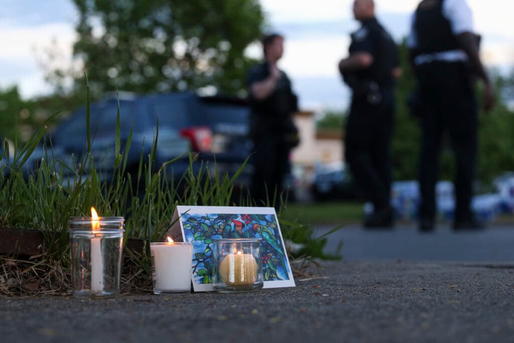 Police walk by a small memorial as they investigate after a shooting