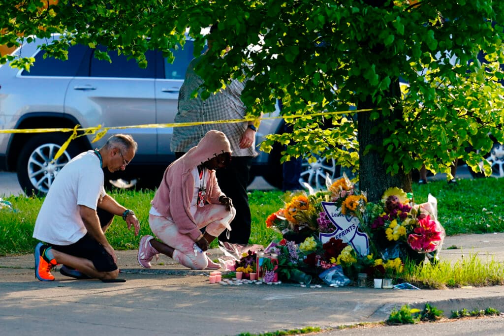 People pay their respects outside the scene of a shooting