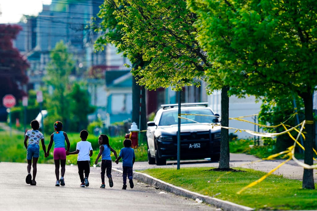 Children walk hand in hand out near the scene of a shooting