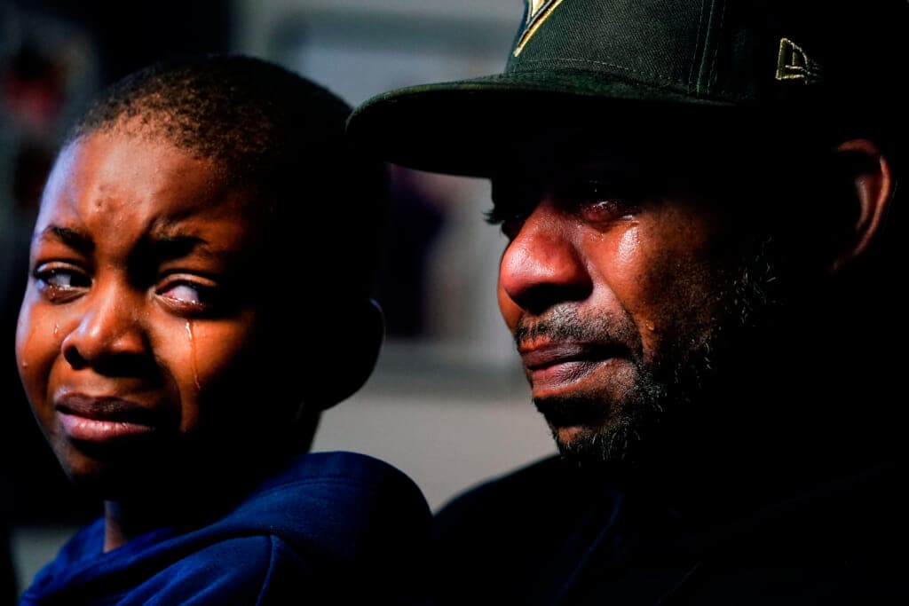 Wayne Jones holds his son Donell while speaking about his mother Celestine Chaney