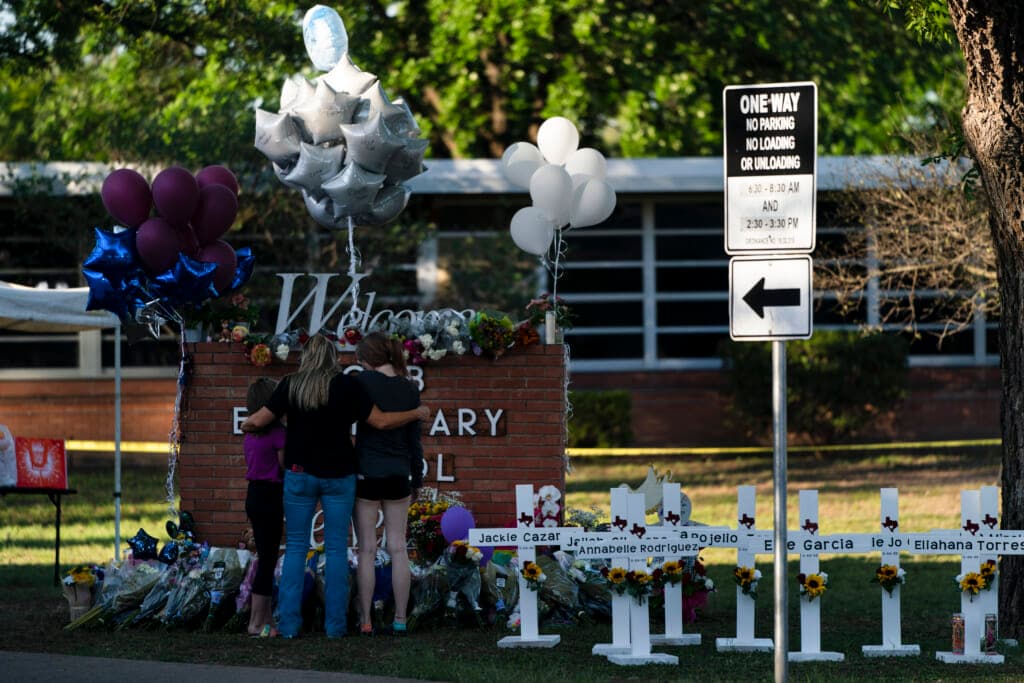 A family pays their respects next to crosses bearing the names of shooting victims