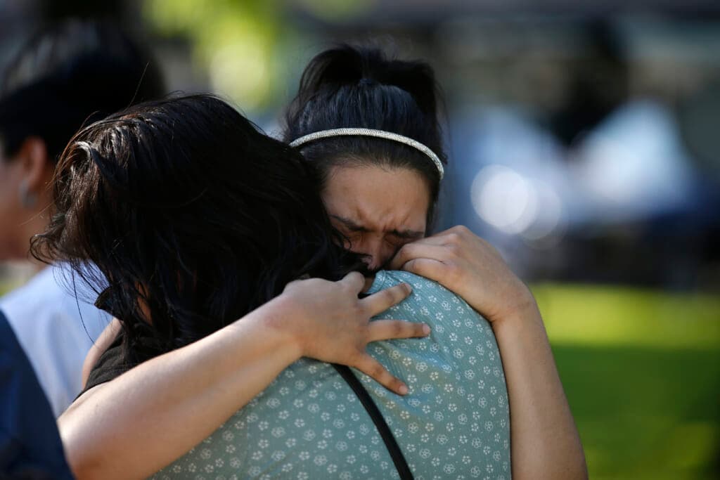 Prianna Ayala weeps as she is embraced at a memorial site