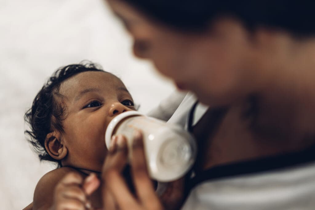 A woman gives a baby a bottle