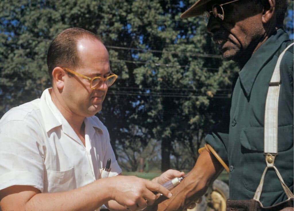 A Black man included in a syphilis study has blood drawn by a doctor in Tuskegee, Ala.