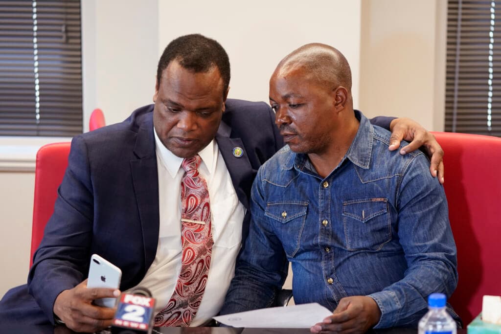 Kent County Commissioner Robert Womack shows Peter Lyoya the broadcast feed in attorney Ven Johnson office