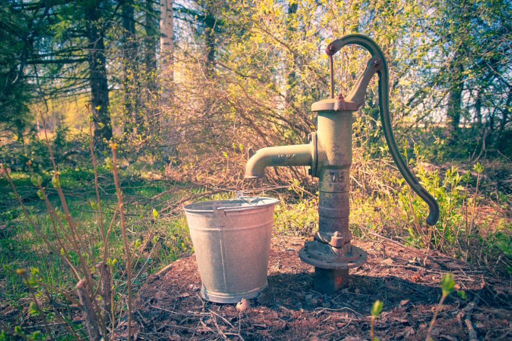 An outdoor pump and water bucket